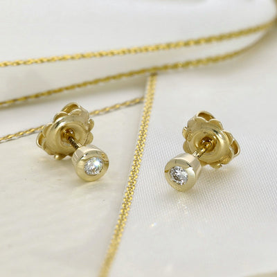 Gold earrings with diamond studs on a white background