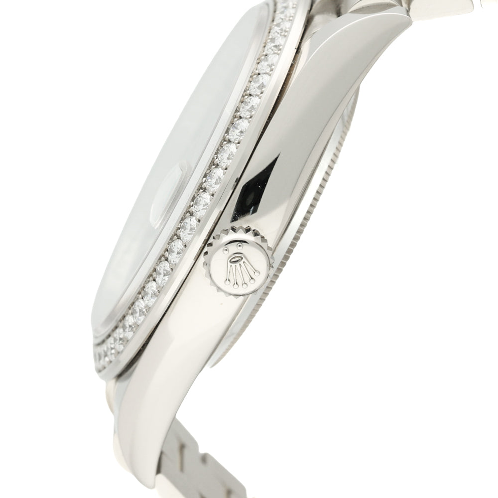Close-up side view of a gold wristwatch with a polished metal case, a bezel set with Diamonds, and a visible Rolex crown logo on the side.