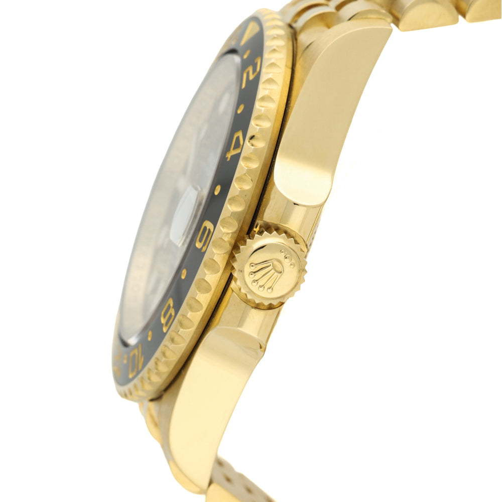 Close-up side view of a gold-tone wristwatch with a black rotating bezel and gold-tone metal bracelet on a white background.